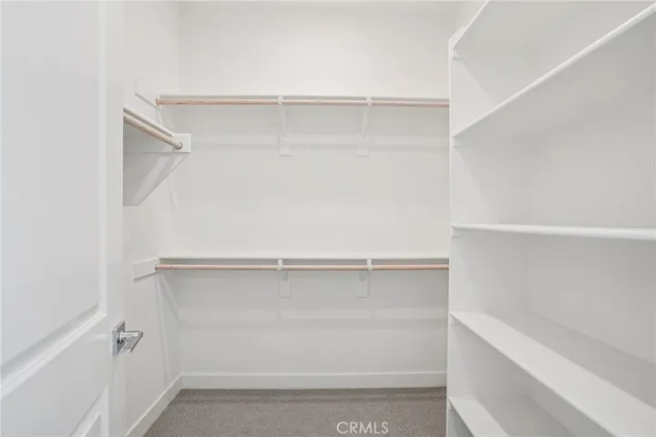 Primary bedroom walk in closet with built in shelves