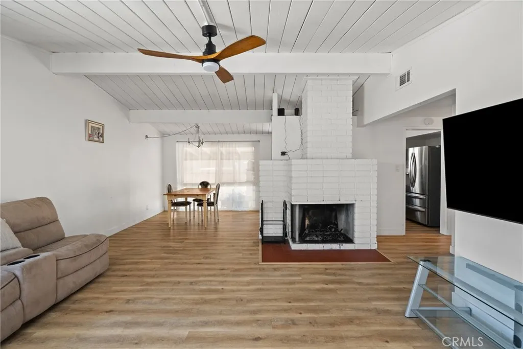 Spacious living room has a fireplace and ceiling fan | Original photo