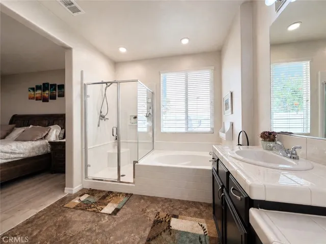 Primary ensuite with soaker tub, walk-in shower, and dual sink vanities, and dressing table
