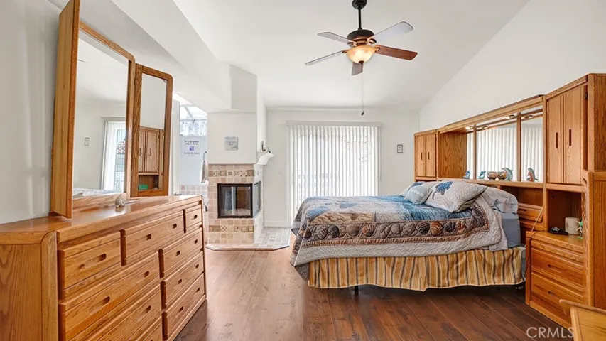 The primary bedroom has vaulted ceilings, a gas fireplace, a ceiling fan and a balcony.