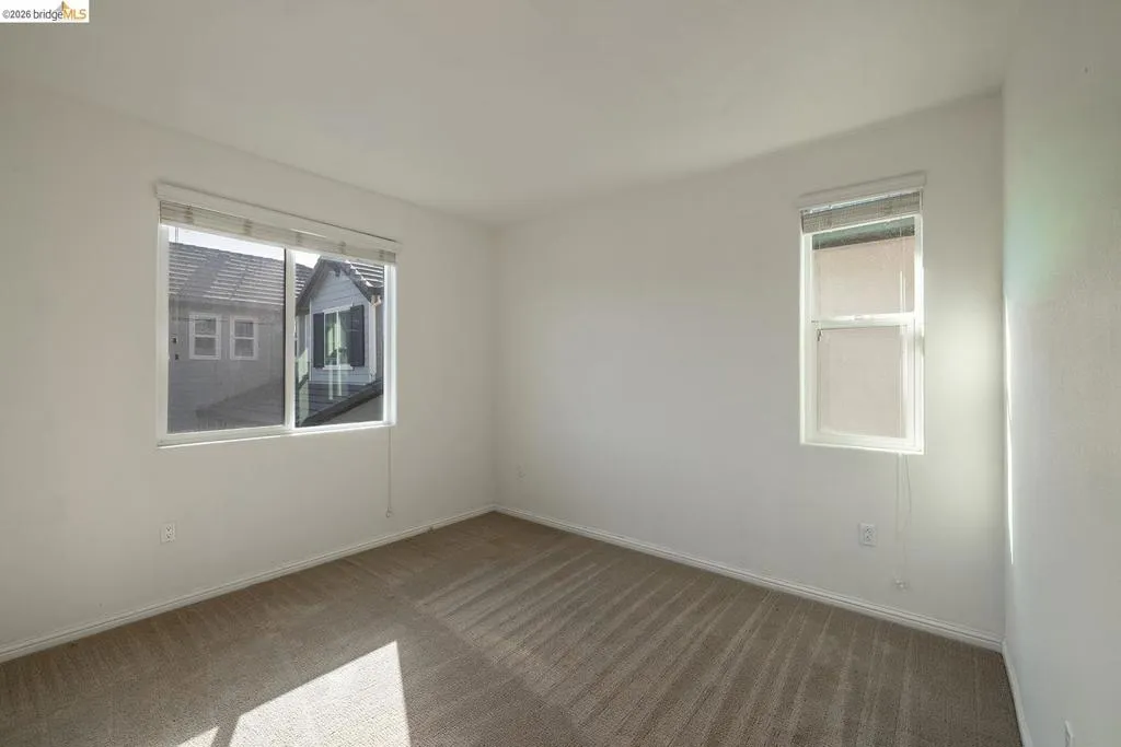 Neutral-toned carpet flooring, white painted walls, and two windows with blinds
