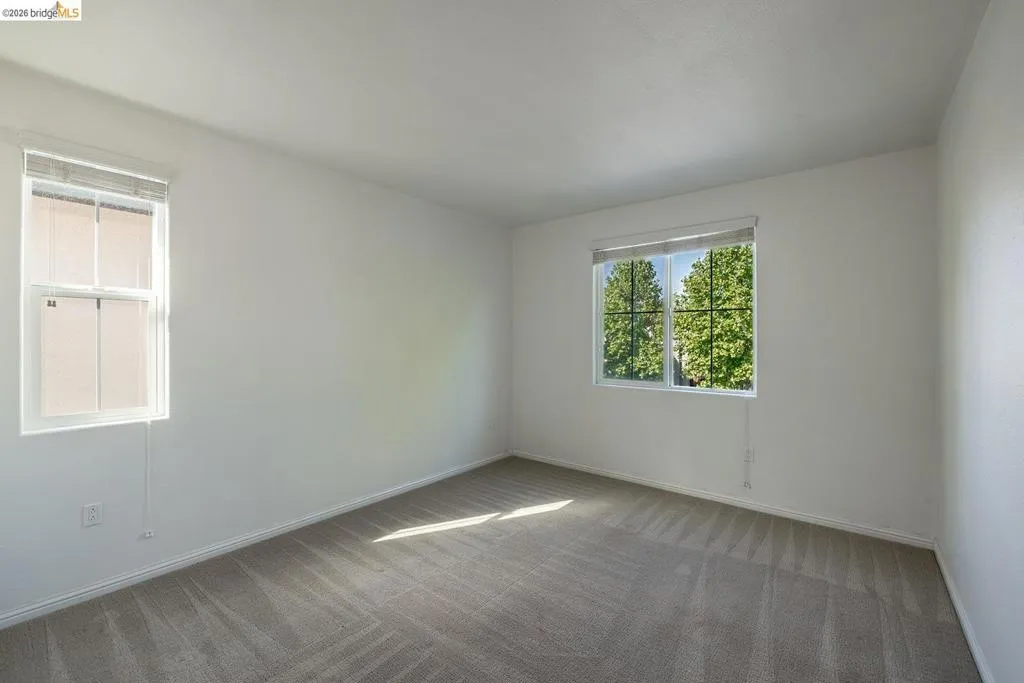 Spacious room featuring neutral carpeting, white walls, and white trim