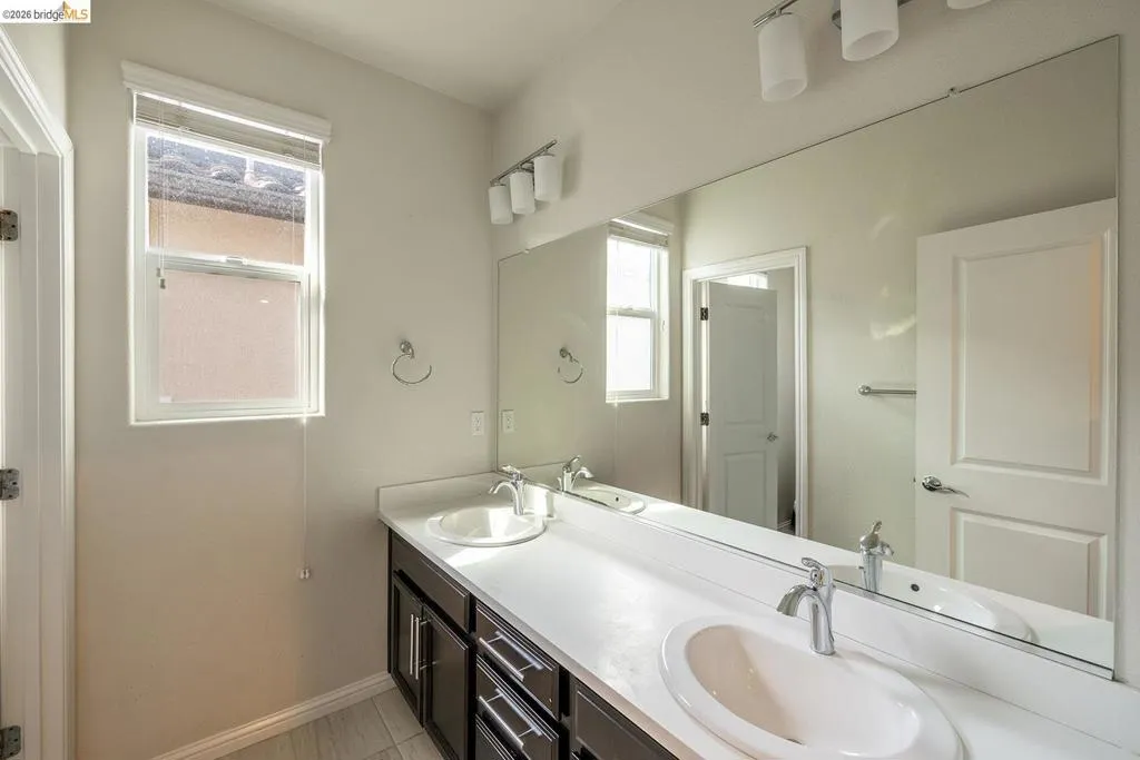 Bathroom featuring a dual vanity with white countertops, undermount sinks, chrome faucets, and dark wood-finish cabinetry