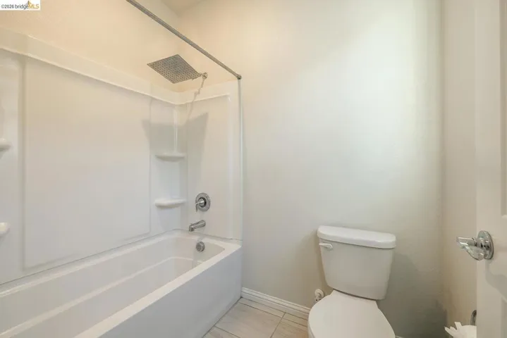 Bathroom featuring a white tub-shower combination with a rain showerhead, chrome fixtures, and integrated shelving