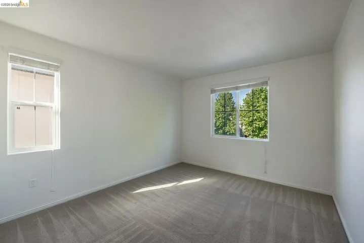 Spacious room featuring neutral carpeting, white walls, and white trim