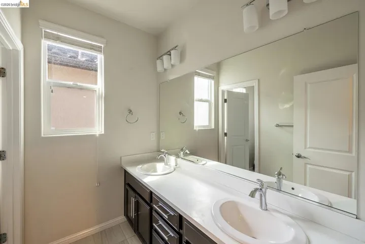 Bathroom featuring a dual vanity with white countertops, undermount sinks, chrome faucets, and dark wood-finish cabinetry