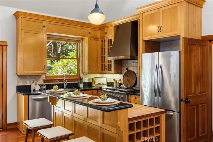 High end appliances and butcher block island with granite breakfast bar and wine rack