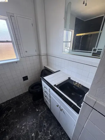 Bathroom featuring tile walls, vanity, a shower stall, and wainscoting