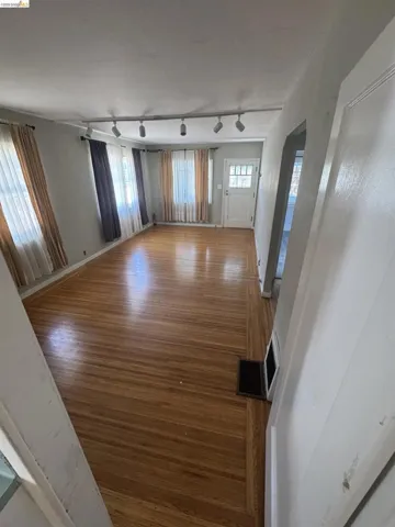 Unfurnished living room with light wood-type flooring and rail lighting