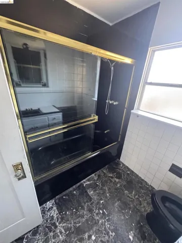 Full bathroom with a shower with door and tile walls