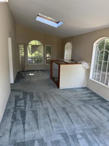 Unfurnished living room with a skylight, carpet, and lofted ceiling