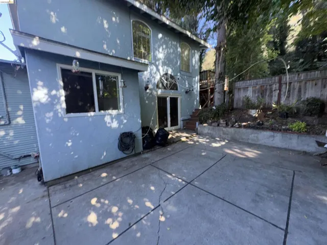 Back of property with stucco siding, stairs, and a patio