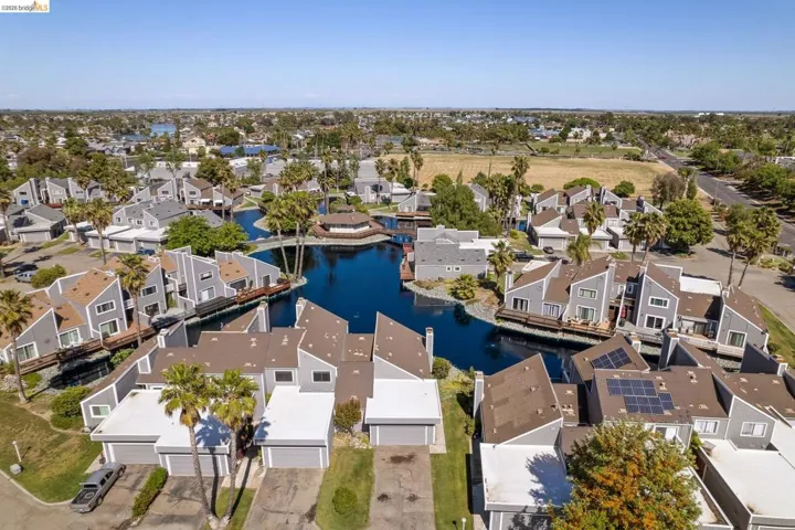 Aerial perspective of a multi-unit residential community featuring a central waterway