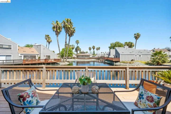 Expansive wood-finish deck with a wood-slat railing overlooking a serene waterway