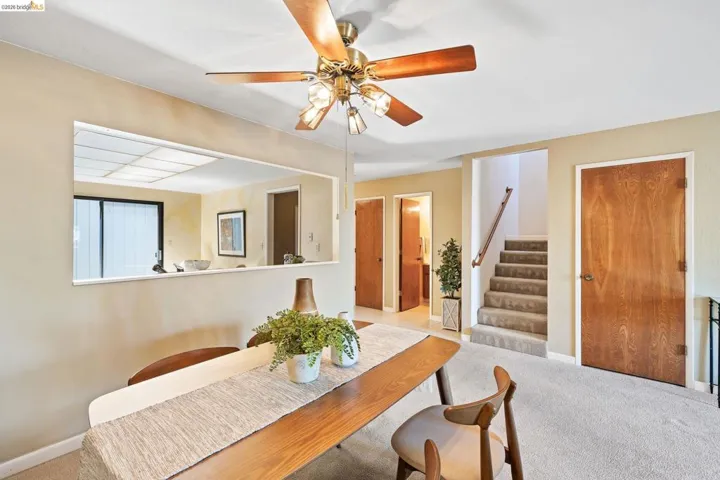 Dining area featuring a ceiling fan with light fixture, carpeted flooring, and a pass-through window opening