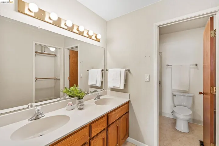 Bathroom featuring a double vanity with light wood-finish cabinetry, a large integrated countertop, and two oval undermount sinks