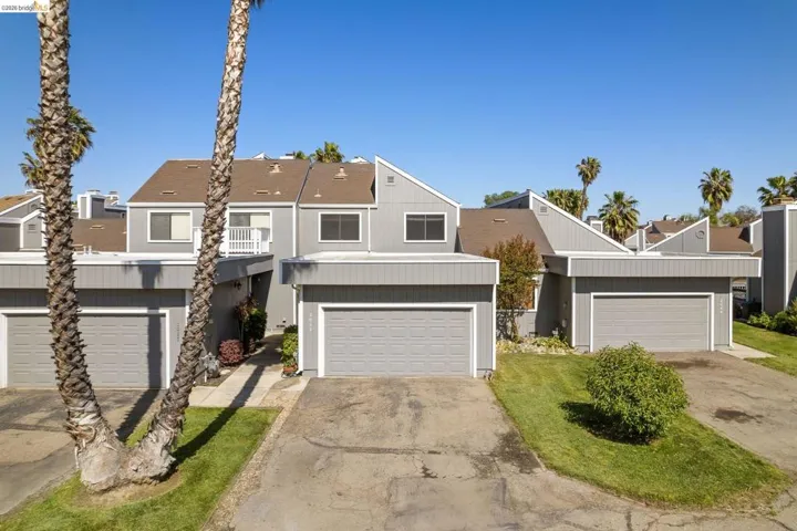 Multi-level property featuring a gray exterior siding and a brown shingled roof