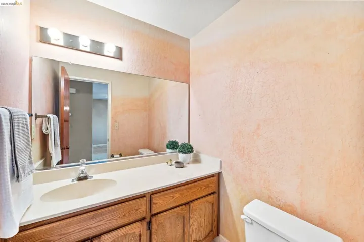 Integrated vanity with a single basin sink, wood-finish cabinetry, and a full-width mirror
