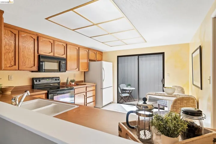 Kitchen featuring wood cabinetry, a dual basin sink, and black appliances including an oven with stovetop and a built-in microwave