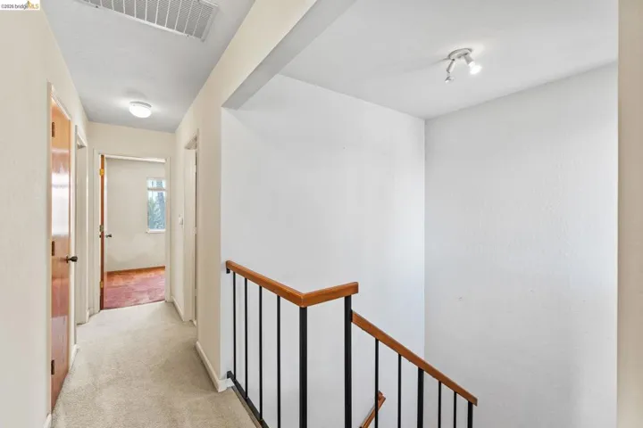 Carpeted hallway featuring a flush-mount ceiling light and wood-finish doors