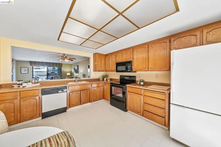 U-shaped kitchen featuring wood cabinetry, tile flooring, and a pass-through window