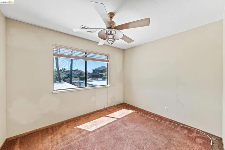Light-filled room featuring a ceiling fan with integrated lighting, a broad window with horizontal blinds, and a carpeted floor