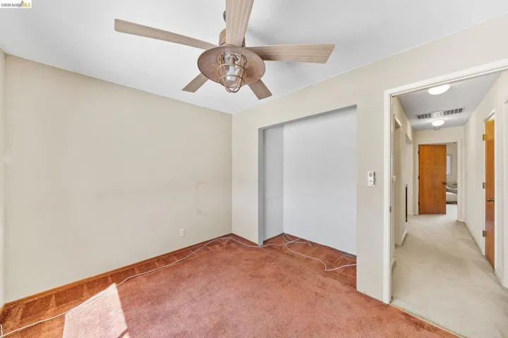 Room featuring a ceiling fan with light fixture, neutral wall paint, and a recessed wall area