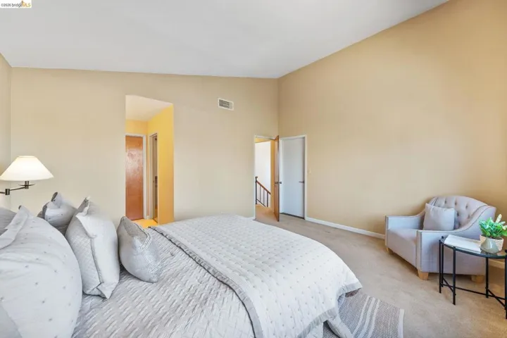 Carpeted bedroom featuring vaulted ceilings and a neutral color palette