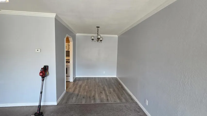 Dining area featuring wood-finish flooring, a contemporary ceiling light fixture, and an arched doorway