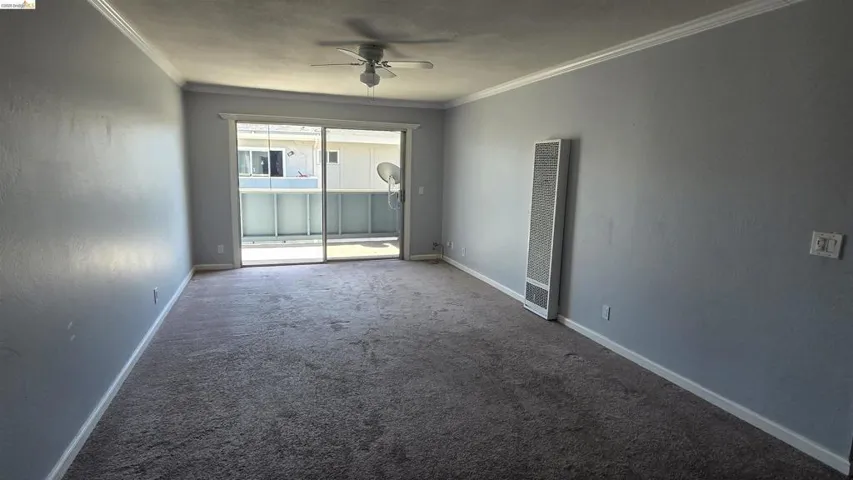 Carpeted living space featuring light gray walls, white baseboards, and white crown molding