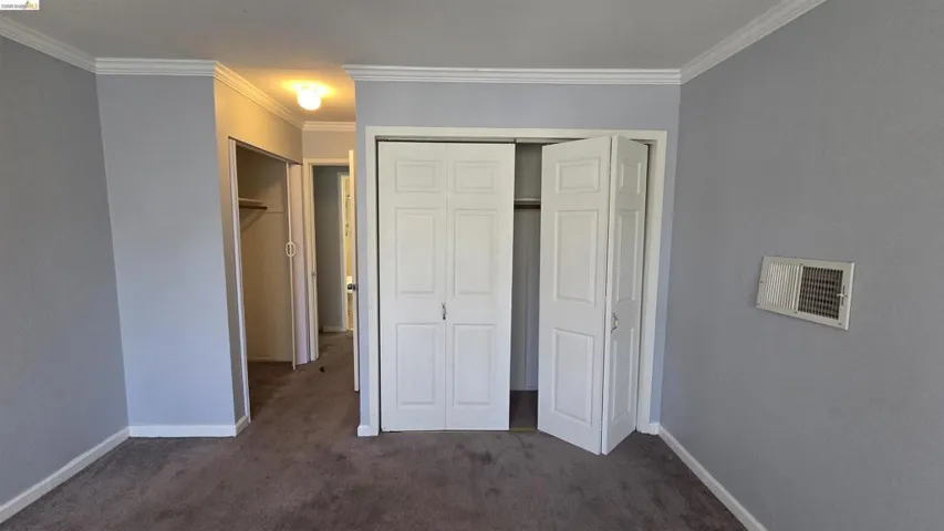 Room featuring light gray walls, white crown molding, and brown carpet flooring