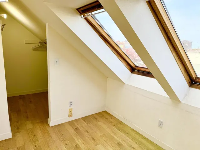 Vaulted attic space featuring wood-finish flooring and multiple skylight windows