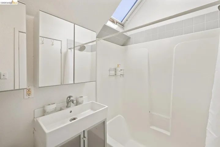 Bathroom with a skylight, vanity, a textured wall, and shower / tub combo