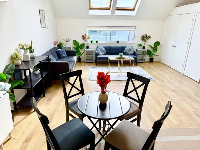 Living area featuring wood-finish flooring, white walls, and two skylights