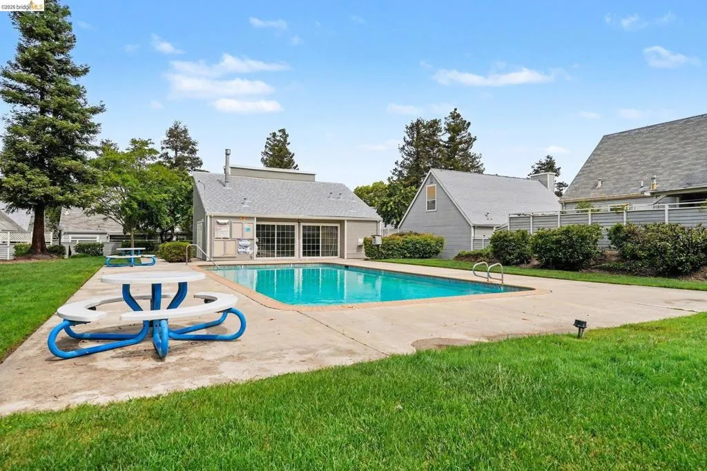 Community pool with surrounding concrete patio and green lawn
