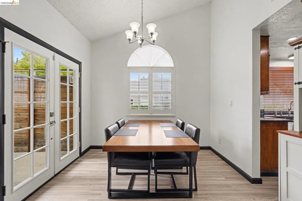 Dining area featuring vaulted ceilings, light wood-finish flooring, and white walls with contrasting dark trim