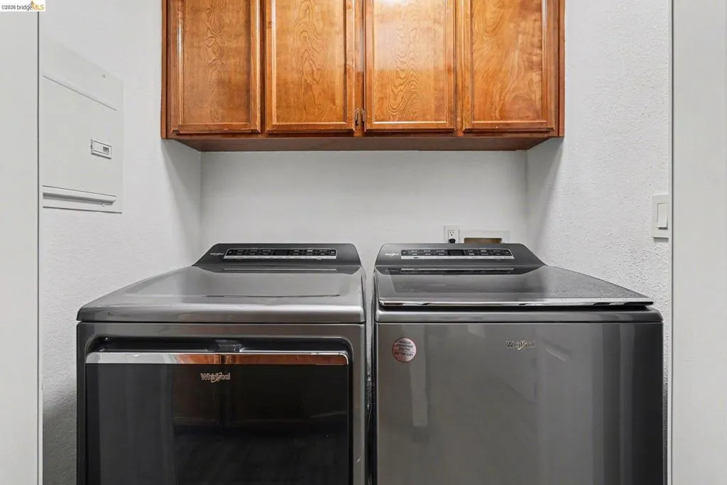 Laundry area featuring built-in wood cabinetry, white walls, and a recessed electrical panel