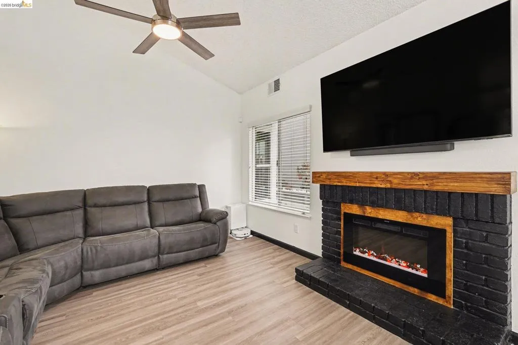 Living area featuring wood-finish flooring, a vaulted ceiling, and a ceiling fan