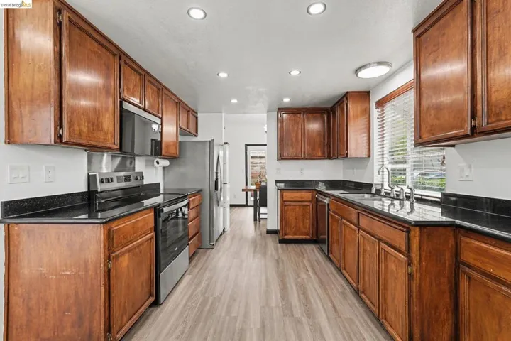 Kitchen featuring wood-finish cabinetry, black countertops, and light wood-look flooring