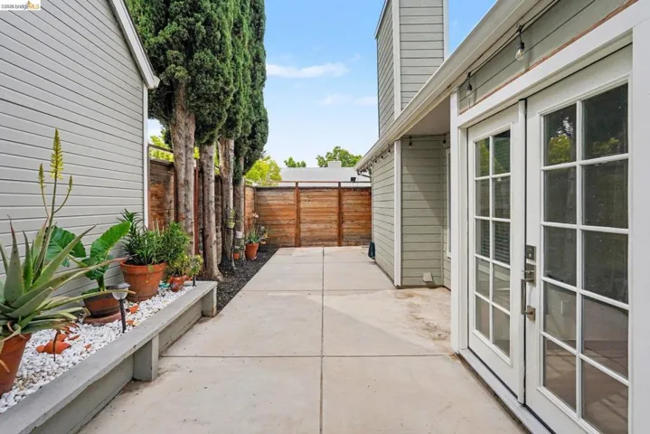 Private courtyard featuring a concrete patio, horizontal slat fencing, and a perimeter planter box