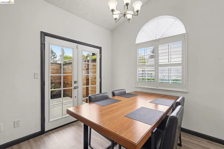 Dining space featuring wood-finish flooring, a contemporary chandelier, and a vaulted ceiling
