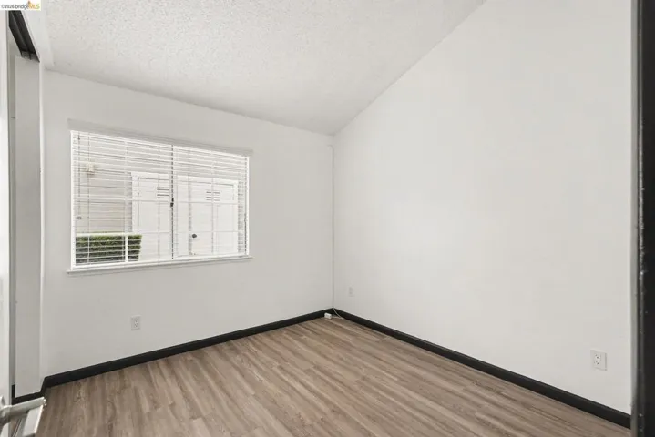 Bright room featuring wood-finish flooring, white walls, and a window with horizontal blinds