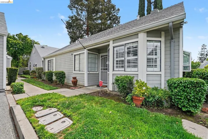 Grey siding exterior featuring multiple windows with louvered shutters, a covered entry, and a pitched roof