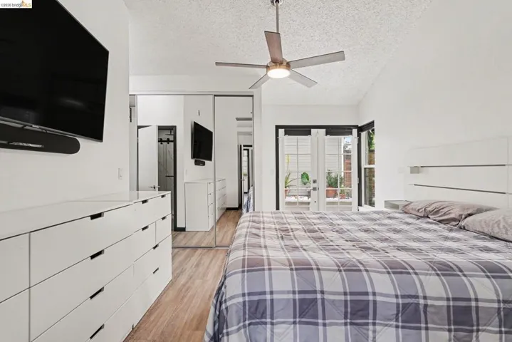 Room featuring wood-finish flooring, a ceiling fan with integrated lighting, and a white flat-panel storage unit