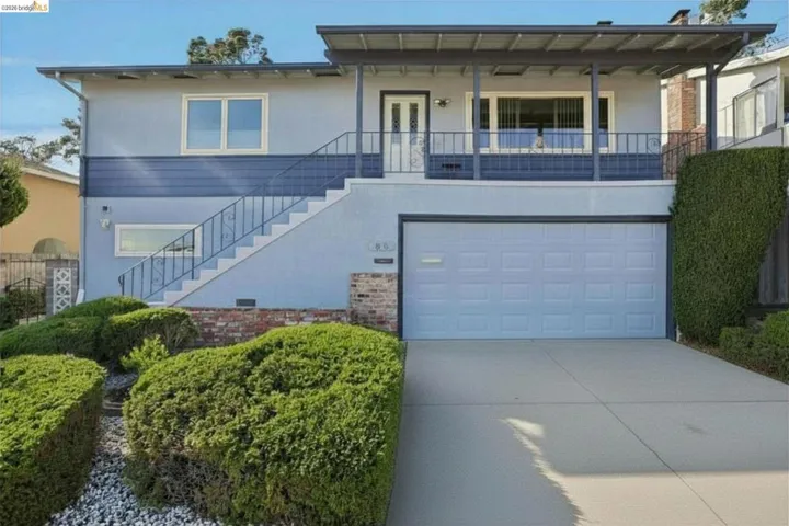Split-level exterior featuring a light blue stucco finish with dark blue horizontal siding accents