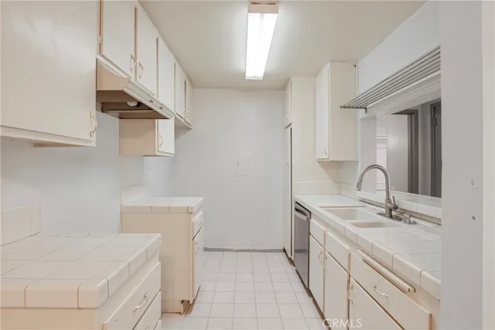 View inside the U-shaped kitchen with cabinets on the left and the sink with dishwasher on the right. The efficient layout maximizes counter space and storage.