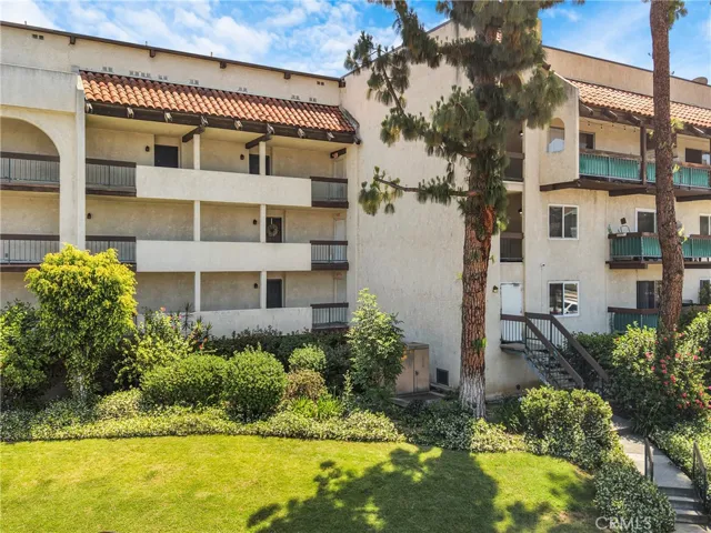 Front view of the three-story condo building as seen from the main street, with the cul-de-sac not visible in this frame. The first-floor unit features access to an underground garage.