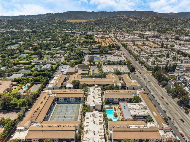Aerial view facing east/west showcasing the surrounding neighborhood, including a local school and White Oak Avenue. The condo's position within this well-connected community is clearly highlighted.