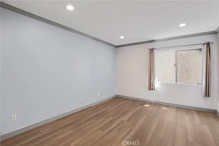 View of the window inside the primary bedroom, bringing natural light into the space. The window offers a pleasant outlook within the unit.