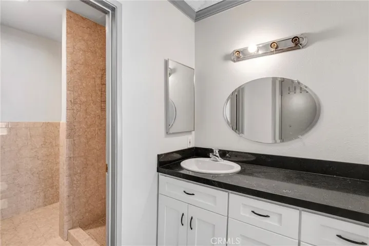 View of the vanity area in the secondary bathroom, featuring built-in storage underneath. The layout maximizes functionality within the available space.